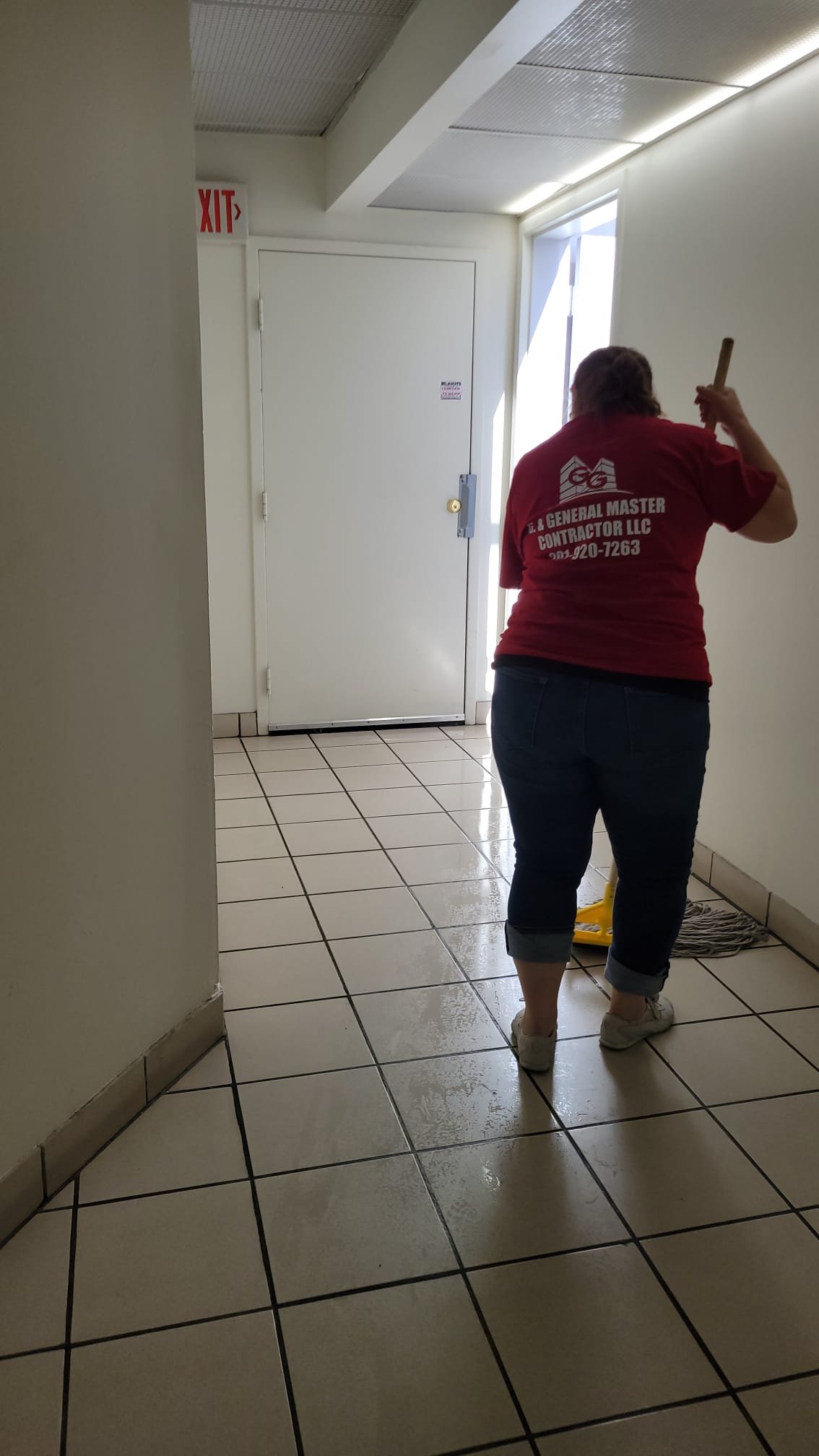 G & General Master Contractor team member mopping a tiled building hallway